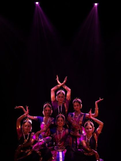 A group of our dancers in a pyramid formation during the Sadhana Classical Dance Festival. The dark stage and purple spotlights create a mystical and enchanting mood.