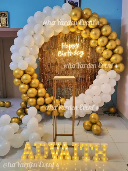 A classic gold and white balloon ring with a gold fringe backdrop and a neon sign.
