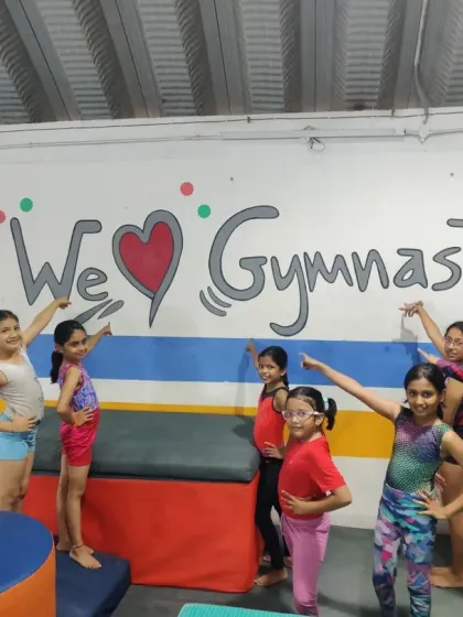 "Fuelled by fun. Powered by passion." Our gymnasts pointing to our "We Love Gymnastics" wall art, which perfectly captures the spirit of our academy.