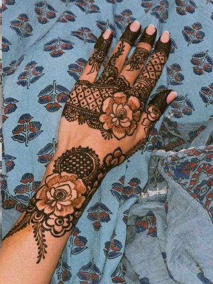 This is one of my favorite styles, combining large, shaded roses with delicate leafy vines and geometric patterns on the fingers. It's a perfect example of modern Arabic fusion henna.