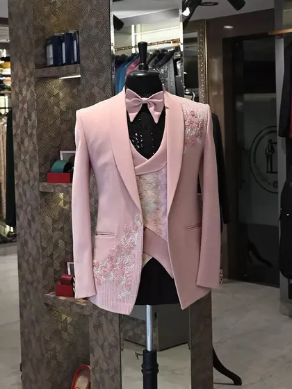 A modern three-piece tuxedo in a soft pink, featuring delicate floral embroidery on the jacket. This is a great option for daytime events or for a groom who wants a departure from traditional colors.
