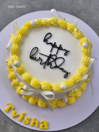 A simple yet cheerful yellow birthday cake with piped borders and delicate ribbon bows.