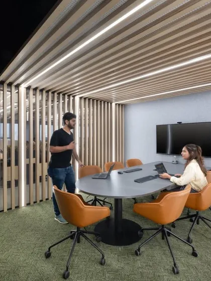This meeting room is enclosed by slatted wood partitions, offering semi-privacy while allowing light and air to circulate. The design is perfect for team meetings that are part of the office buzz.