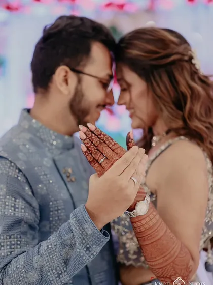 A beautiful moment from an engagement ceremony, where the couple shares a quiet connection, their hands showing the intricate mehendi.