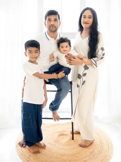 A standing family portrait that feels both classic and modern. The simple color palette of their clothes and the bright lighting create a clean, elegant look.