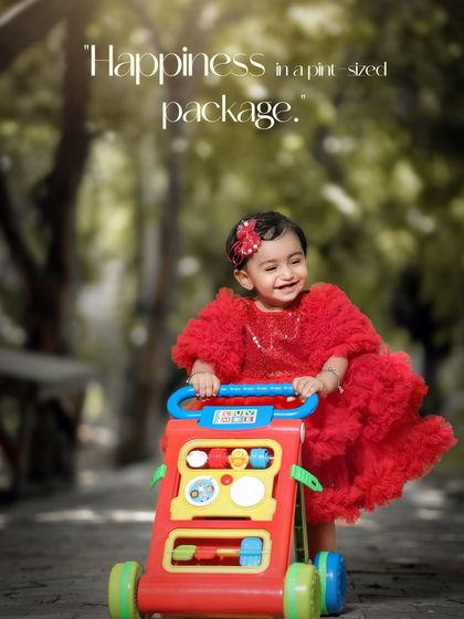 Happiness in a pint-sized package. A joyful girl in a red dress takes her first steps with a colorful walker toy.