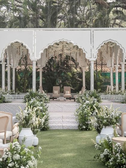 The view down the aisle towards the mandap, lined with large white pots filled with lush greenery and white flowers.