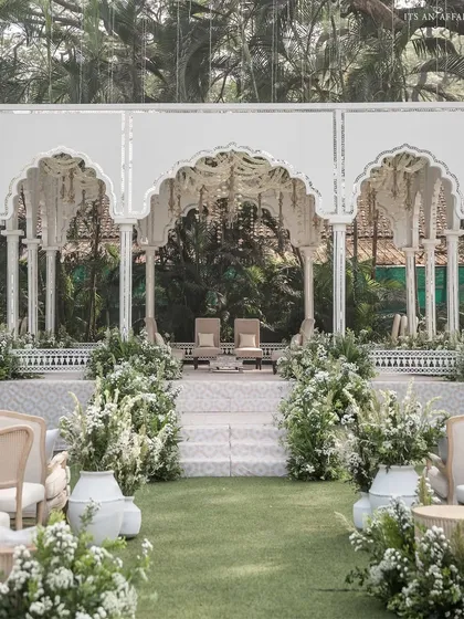 The view down the aisle towards the mandap, lined with large white pots filled with lush greenery and white flowers.