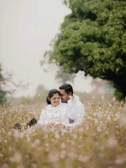 A couple shares a tender moment, sitting together in a beautiful field of white wildflowers. This style is perfect for soft, natural, and romantic pre-wedding portraits.