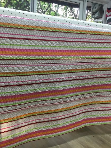 A close-up of the striped quilt, showing the different quilting patterns used on each stripe.