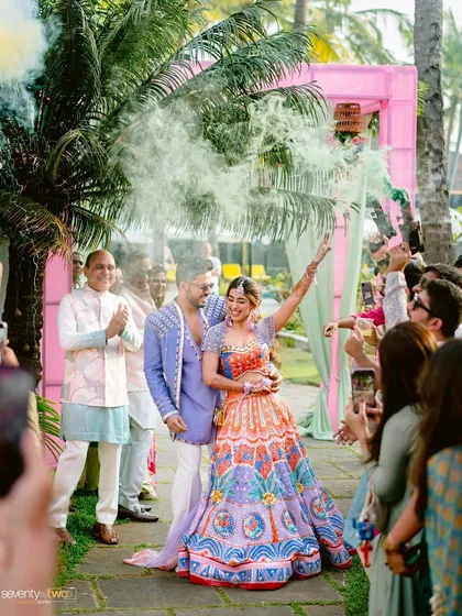 The couple makes a grand entrance to their Mehendi party through a cloud of smoke, with guests cheering them on.