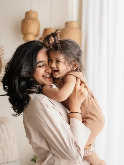 A sweet hug between mother and daughter. The soft natural light and their genuine smiles make this a truly beautiful and emotional portrait.