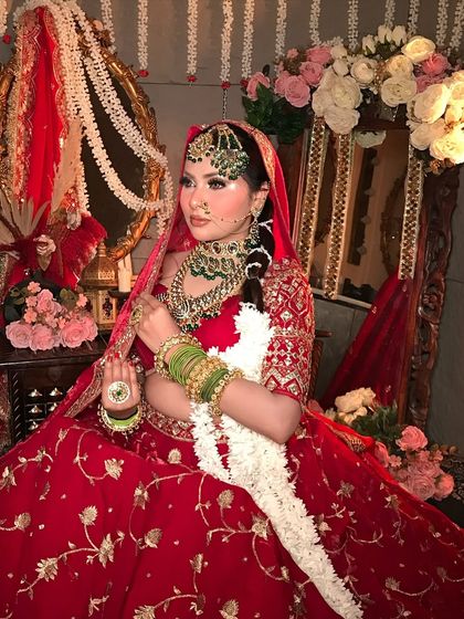 A full view of a traditional bride in her element. The makeup is designed to be stunning from every angle, complementing the grand setting and ornate bridal attire.