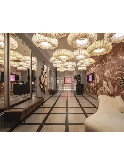 The full view of the dramatic entrance lobby, where the ceiling light installation is reflected in large mirrors, amplifying its impact and creating a sense of infinite space.