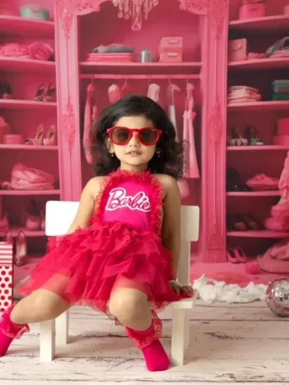 It's a Barbie world, and this little one owns it. My Barbie-themed shoots are all about capturing that fun, confident personality with a vibrant pink set and stylish props like these heart-shaped sunglasses.
