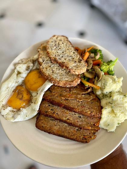 A beautiful breakfast plate put together by a fan, featuring thick slices of our juicy pork meatloaf. It's paired with runny eggs, sourdough toast, and mashed potatoes for a wholesome, protein-packed start to the day.