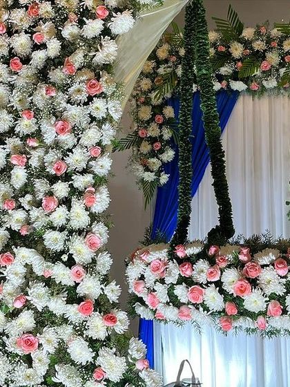 A close-up of a hanging cradle (uyyal) decorated with pink and white flowers for a naming ceremony. The floral arch in the background completes the beautiful picture.