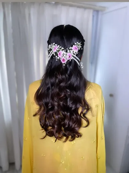The back view of this lovely haldi hairstyle. The floral and pearl accessory adds a beautiful, traditional touch to the soft, open waves.