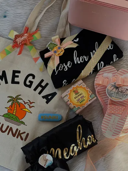 A personalized beach bachelorette hamper for "Megha". This set includes a custom tote bag, flip-flops, and other beach essentials, all tied together with the fun #SUNKI wedding hashtag.