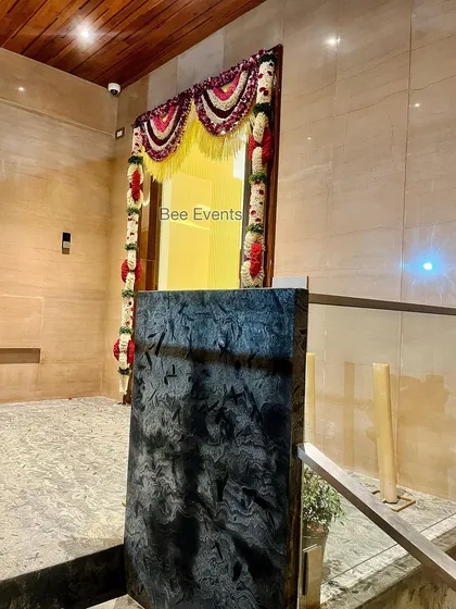 A wide shot of a doorway adorned with traditional flower hangings. The decor adds a festive touch while allowing a glimpse into the beautifully lit home interior.
