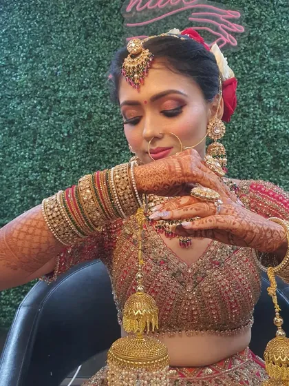 The final touches are everything. This bride is adjusting her kalire, showing off her intricate henna and the complete look with jewellery, hair, and flawless makeup.