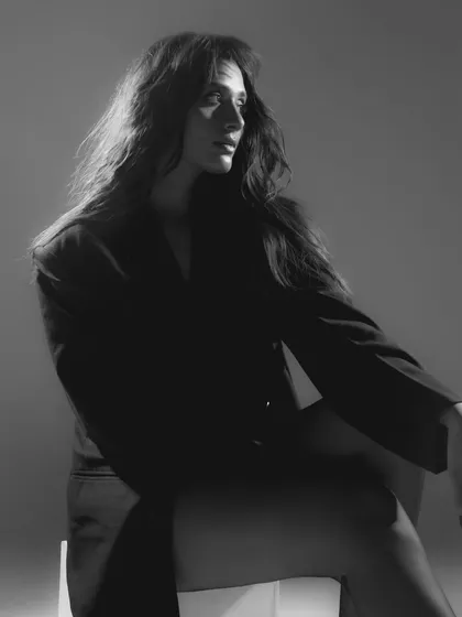 A classic black and white portrait. The soft lighting from the side beautifully models her features, and the wind-blown hair adds a sense of effortless grace.