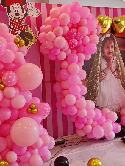 A close-up of a Minnie Mouse-themed party, showcasing the intricate pink balloon sculptures and a photo of the birthday girl.