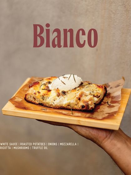 The Bianco slice, a white pizza with roasted potatoes, mushrooms, ricotta, and a drizzle of truffle oil.