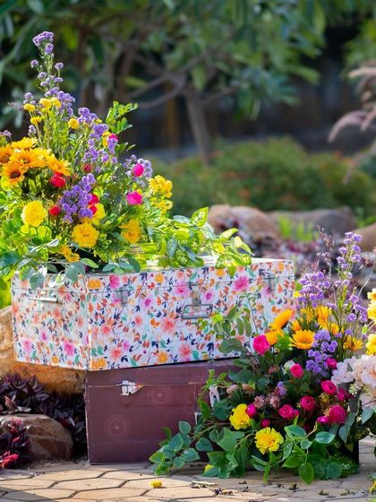 The floral trunks add a vintage and whimsical touch to the garden decor of the Haldi ceremony.