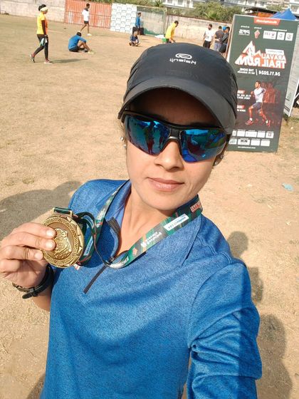 A participant proudly shows off her finisher's medal after completing her longest distance ever, 30km, at the Aravali Trail Run.
