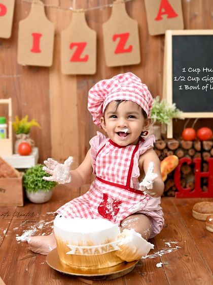 A tiny chef with a very happy, frosting-covered smile. This bakery-themed cake smash is a wonderfully creative way to celebrate a first birthday, complete with a chef's hat and apron.