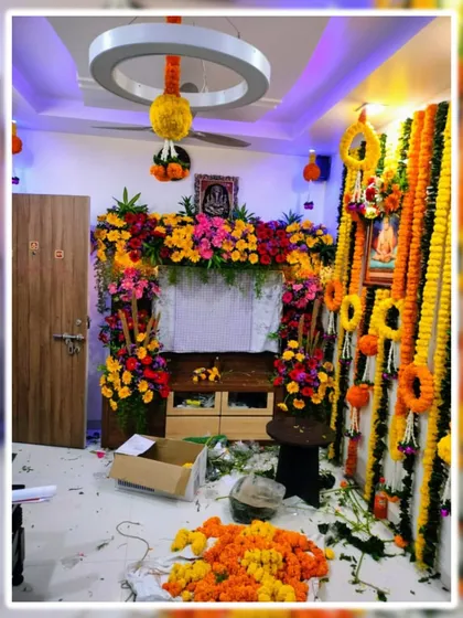 A behind the scenes look at us creating a full room decoration for a festival. The space is being transformed with marigold garlands and a colorful floral frame, showing the scale of our home decoration services.