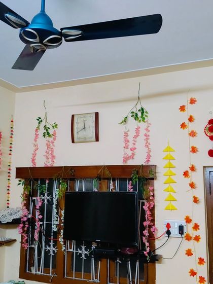 A view of a room corner decorated for a Kalpasutra welcome. I used the space around the window and television to add colorful hangings and artificial flower vines.
