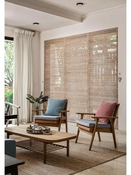 A simple and serene seating arrangement in the living room. The natural wood chairs and coffee table are complemented by banana fiber blinds, which filter the light beautifully and add to the room's earthy, boho vibe.