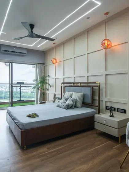 A wide view of the bedroom, showing the balance between the structured wall paneling, the sleek TV unit, and the soft, comfortable furnishings. Every detail is deliberate.