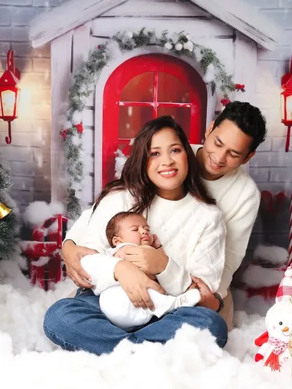 A warm family portrait from a Christmas session, with the parents lovingly holding their new baby.