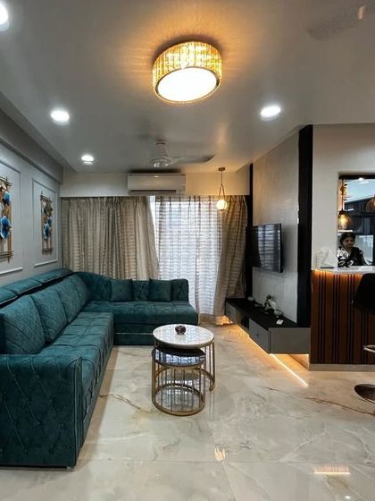 The living room in the evening, with all the lights on. The chandelier, spotlights, and indirect lighting in the TV unit and ceiling work together to create a warm and inviting ambiance.