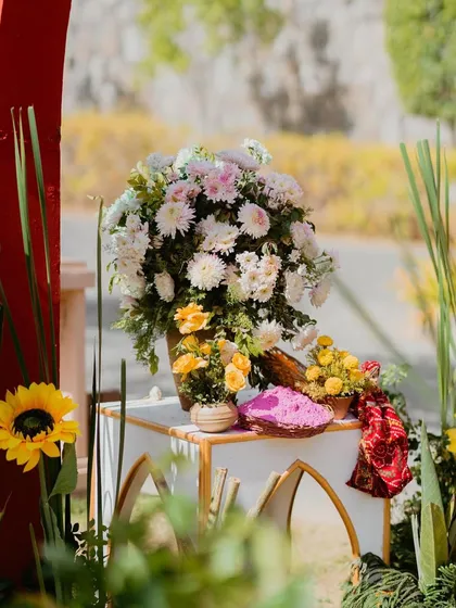 A floral arrangement with white and yellow chrysanthemums, sprinkled with pink Holi powder for a unique and festive touch.