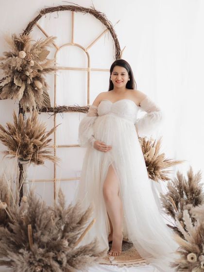 A radiant mother-to-be glowing in our airy, bohemian studio set. The beautiful white gown and rustic decor create a timeless and elegant maternity portrait.