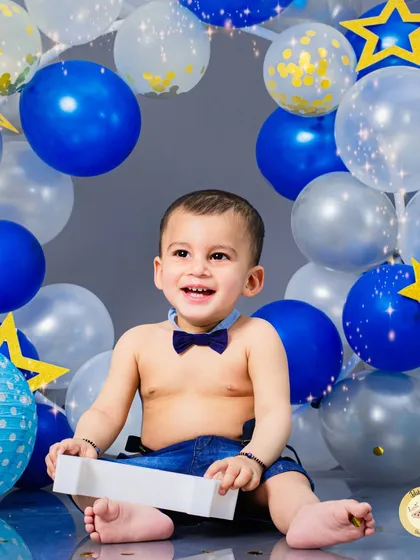 A joyful, classic birthday portrait. The simple background and happy expression make this a timeless photo to remember his first year.
