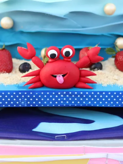 A close-up of the cheeky red crab figurine on the edible sand.