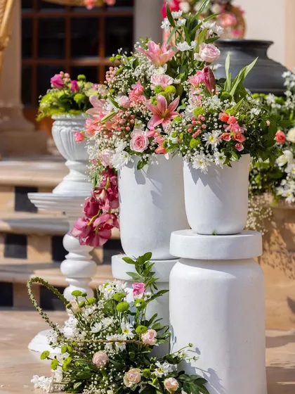 A close-up of the tiered floral arrangements on the steps, showcasing a mix of lilies, roses, and orchids in a fresh pink and white color palette.