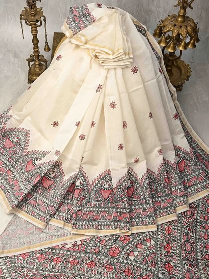 This unique Kalamkari saree features intricate Madhubani-style folk art motifs along the border and pallu. The combination of pink and grey on an off-white base is both traditional and modern.