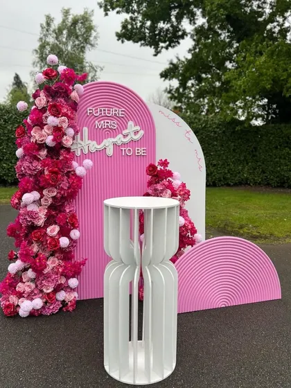 A fun and vibrant bachelorette party backdrop inspired by the popular Barbie theme. This setup includes custom pink arched panels, floral arrangements, and a 'Future Mrs' neon sign for the bride-to-be.