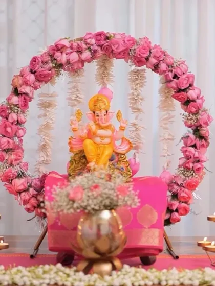A delicate and pretty Ganpati decoration with a ring of pink roses and hanging jasmine flowers. The pink silk cloth on the pedestal completes this soft and elegant look.
