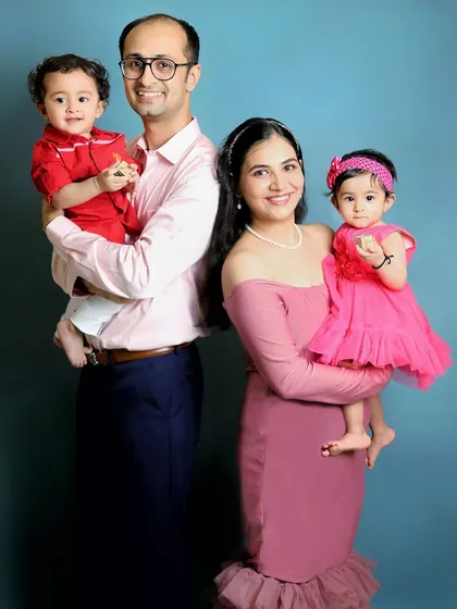 A lovely studio portrait of a family with their one-year-old twins. Coordinating outfits in pink and red makes for a vibrant and cohesive family photo.