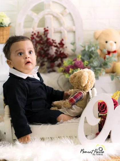 A moment of quiet charm during a first birthday session. This little boy looks so dapper and sweet sitting on a miniature bed with his teddy bear.