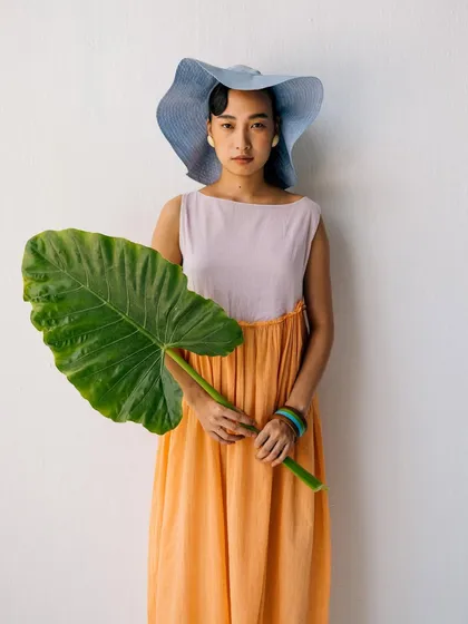A colorful portrait for Label Rama. The model holds a large leaf, adding a natural, tropical element to the studio shot that complements the pastel-colored dress.