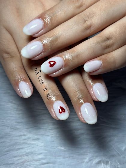A soft and sweet look with milky white nails and a simple, tiny red heart accent.