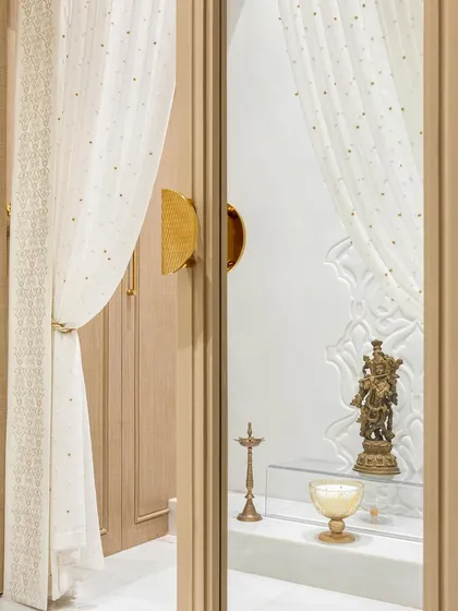 A peek into the serene, all-white pooja room. The delicate carvings on the back wall and the soft, ethereal curtains create a space that feels both divine and deeply peaceful.